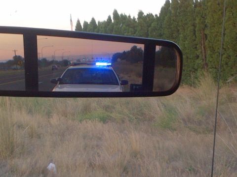 2003 Ford F-150 - A police car is seen in the side mirror, its emergency lights flashing as it follows on the road.