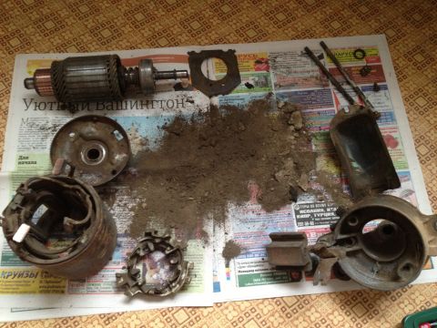 1987 Ford Bronco - Disassembled starter motor components are spread out on newspapers, covered in dirt and debris.