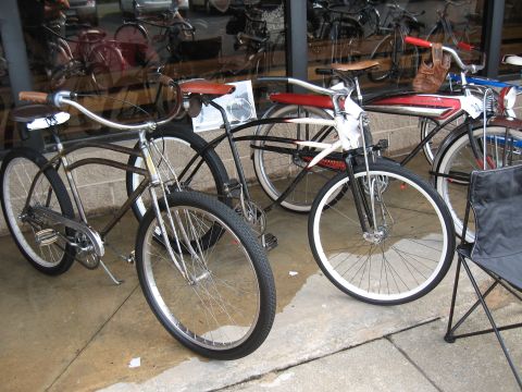 Several vintage bicycles parked outside a shop, some with chrome fenders and leather seats