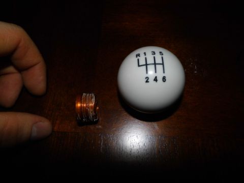 2011 Ford Mustang - White 6-speed shift knob and a small copper coil are shown on a wooden surface.