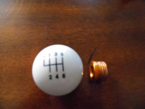 2011 Ford Mustang - A white shift knob with a 6-speed gear pattern is shown next to a small copper-colored spring.