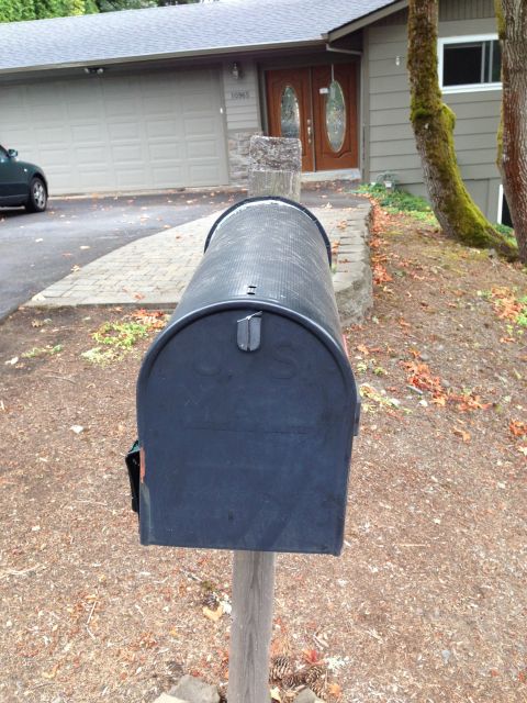1992 Ford F-150 - A black U.S. Mail curbside mailbox on a weathered wooden post at the end of a driveway, with a ranch-style house, two-car garage door and m…