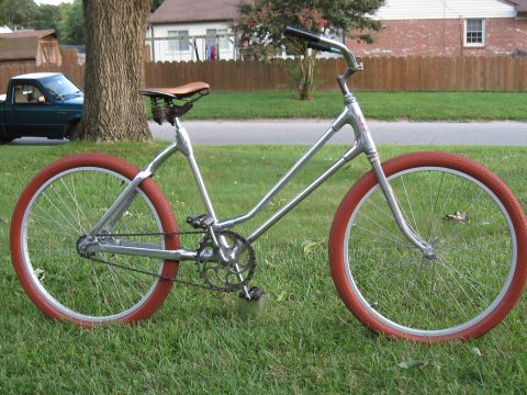 Silver cruiser bicycle with red tires and brown leather seat