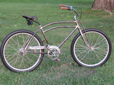 Rusty metal bicycle with brown handlebars and seat, parked on grass