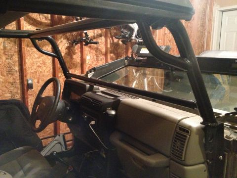 2005 Jeep Wrangler - Interior view of a Jeep Wrangler, highlighting the dashboard and a black roll cage structure.