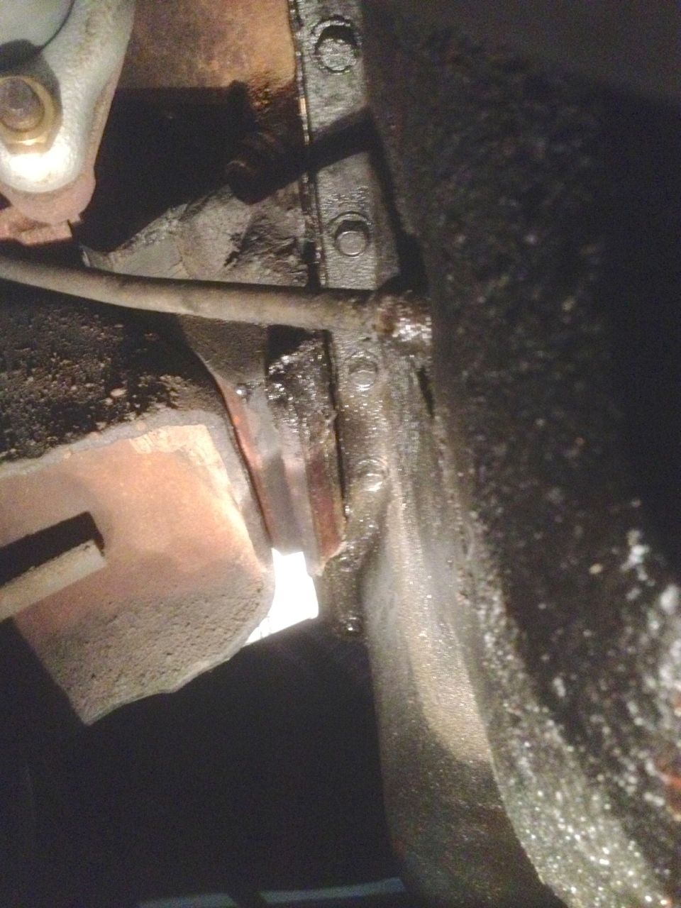 Close-up of greasy engine parts with bolts and a hose