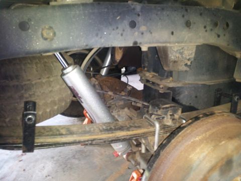 2003 Nissan Frontier - Close-up view of the rear suspension system of a vehicle, showing leaf springs and a shock absorber.