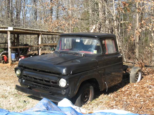 Black pickup truck with missing rear end, parked outdoors near a shed