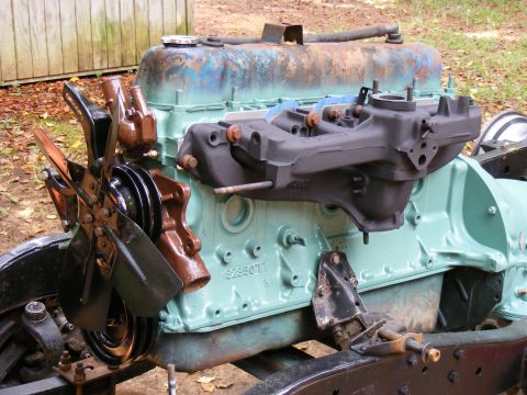 Engine block painted light green with a fan and intake manifold attached. Some rust on the valve cover