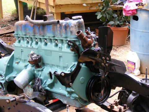 Teal V8 engine block with blue and rust-colored valve covers, fan, and distributor visible