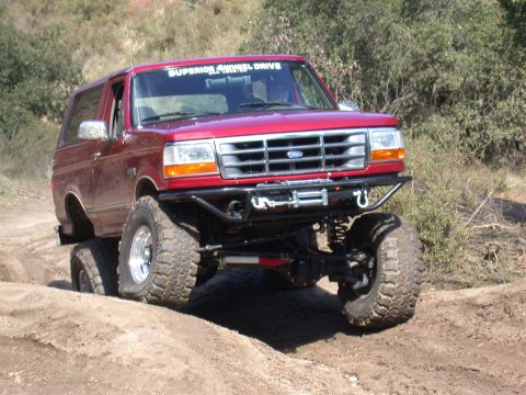 1996 Ford Bronco - This modified Ford Bronco navigates a challenging off-road course with its upgraded suspension and tires.