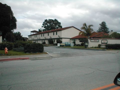 1994 Ford Crown Victoria - A green sedan is parked in front of a motel with a Spanish-style roof. The vehicle appears to be from the early 1990s.