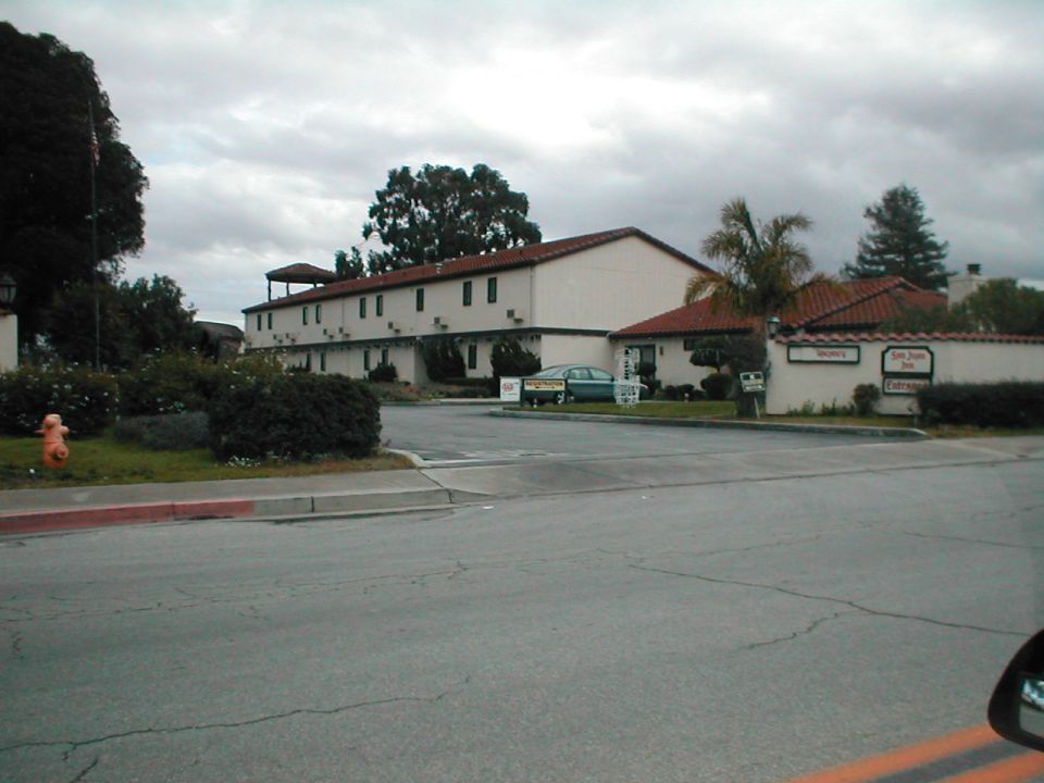 Green sedan parked in front of a motel, likely 1990s model
