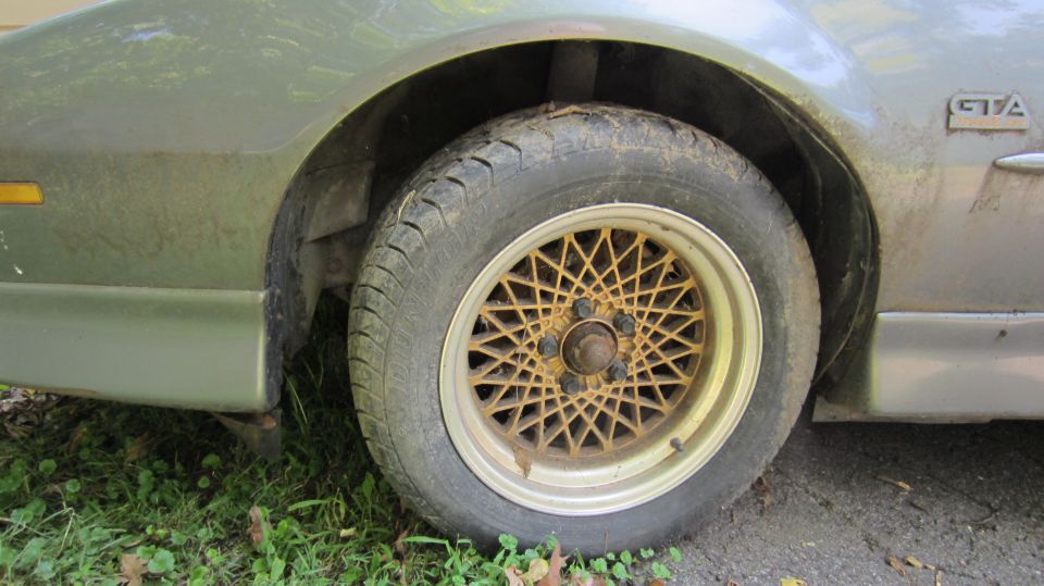1987 Pontiac Firebird GTA side view showing a gold mesh wheel and part of the front fender