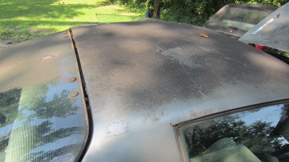 Worn car roof with visible seam and another vehicle in background
