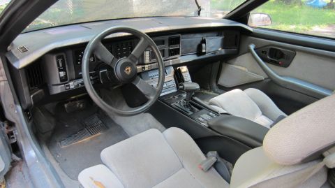 1987 Pontiac Firebird - The interior of a 1987 Pontiac Firebird shows its grey cloth seats and dashboard from the passenger side.