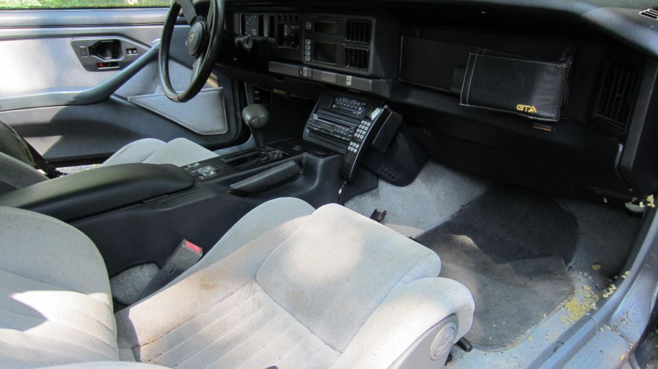 1987 Pontiac Firebird interior showing dashboard, seats, and center console with aftermarket radio