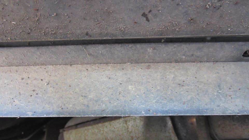 Underside of a vehicle with a metal bar and some dirt