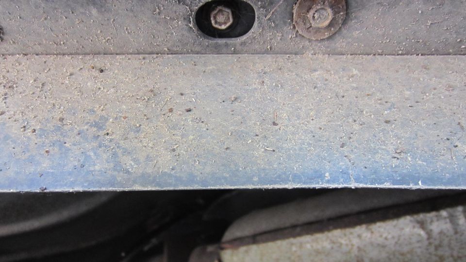 Close-up of dusty metal underside with two bolts visible