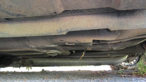 1987 Pontiac Firebird - Underside view of a car's chassis and exhaust system, with a wheel visible on the right side.