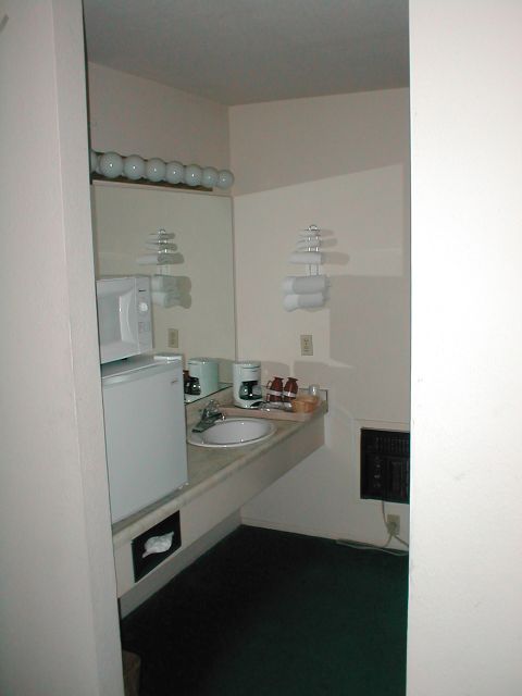 1994 Ford Crown Victoria - This hotel room sink area includes a microwave, mini-fridge, coffee maker, and a mirror reflecting the light fixture.