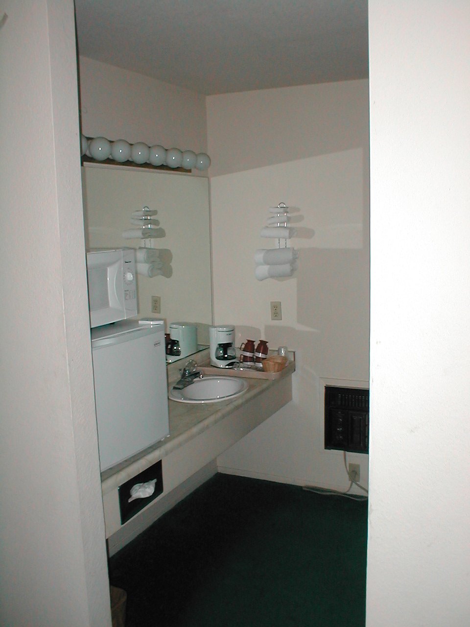 Hotel room sink area with microwave, mini-fridge, coffee maker, and mirror