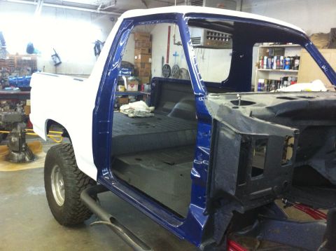 1982 Ford Bronco - A truck is undergoing restoration in a workshop, with its doors open and interior exposed.
