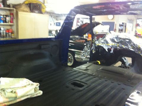 1982 Ford Bronco - View from inside a blue pickup truck bed, looking towards a classic car with its hood up.