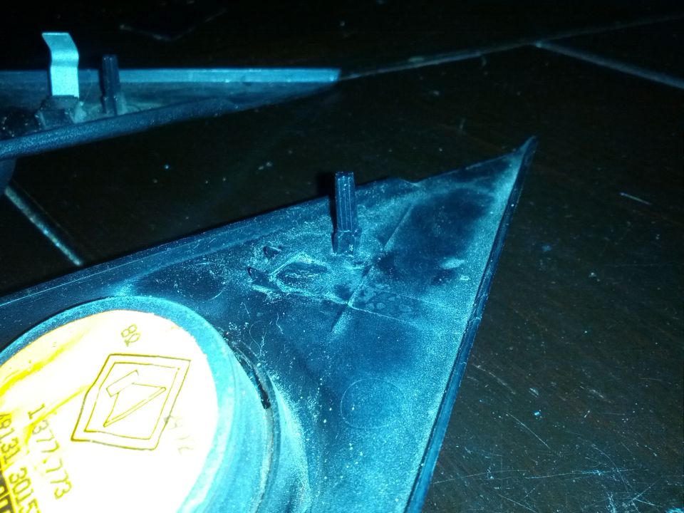 Close-up of a black plastic trim piece with a small black clip sticking up. There's a yellow sticker with a lightning bolt symbol