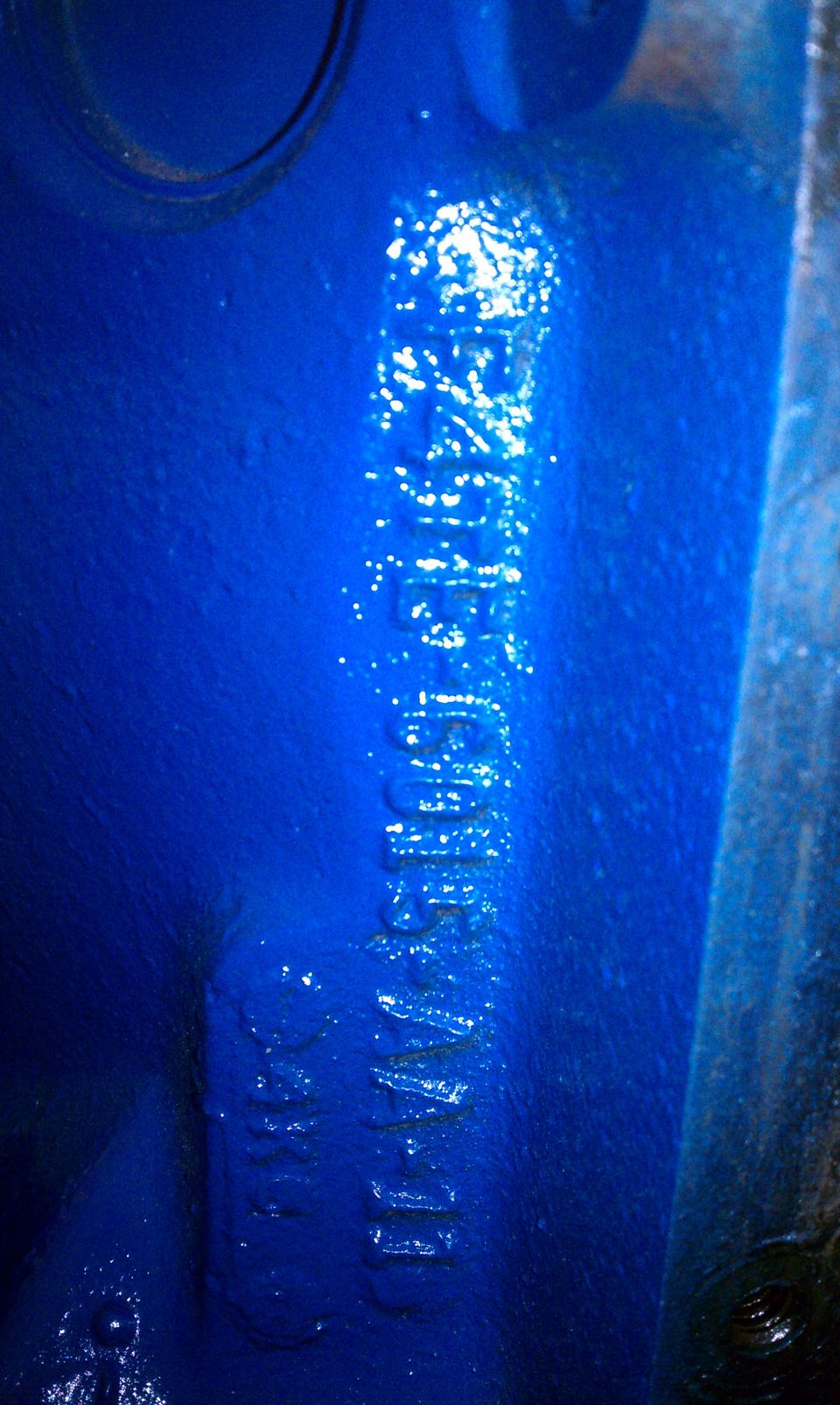 Close-up of blue engine block with stamped casting numbers