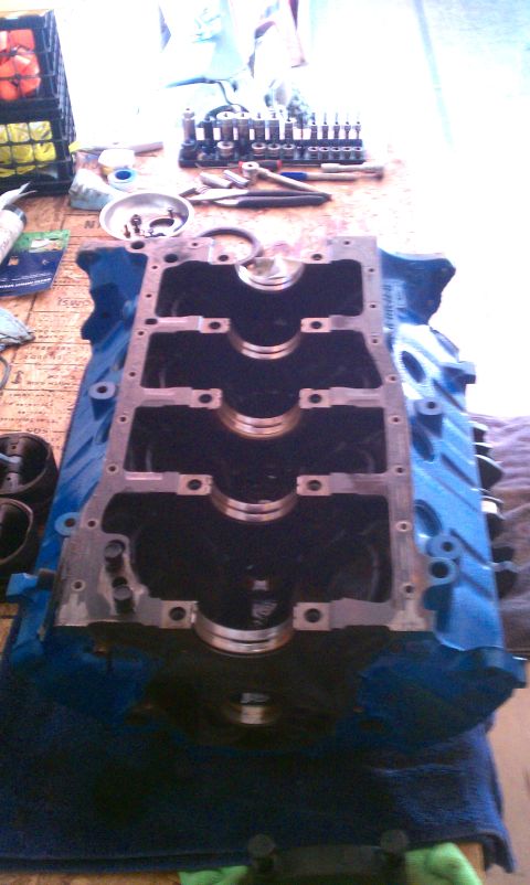 1996 Ford Bronco - A disassembled engine block sits on a table, surrounded by tools and a blue cloth. The Supermotors.net logo is visible at the bottom.