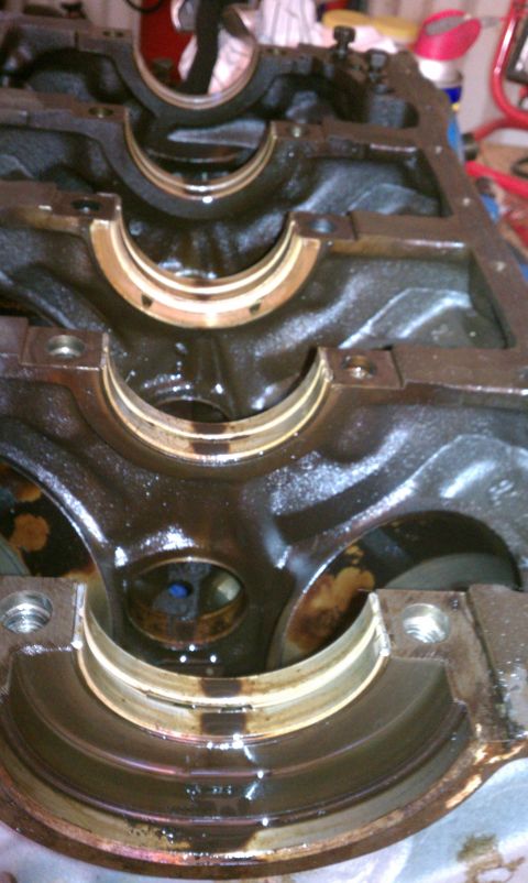 1996 Ford Bronco - Close-up view of an engine block's crankshaft bearing saddles, showing wear and oil residue.
