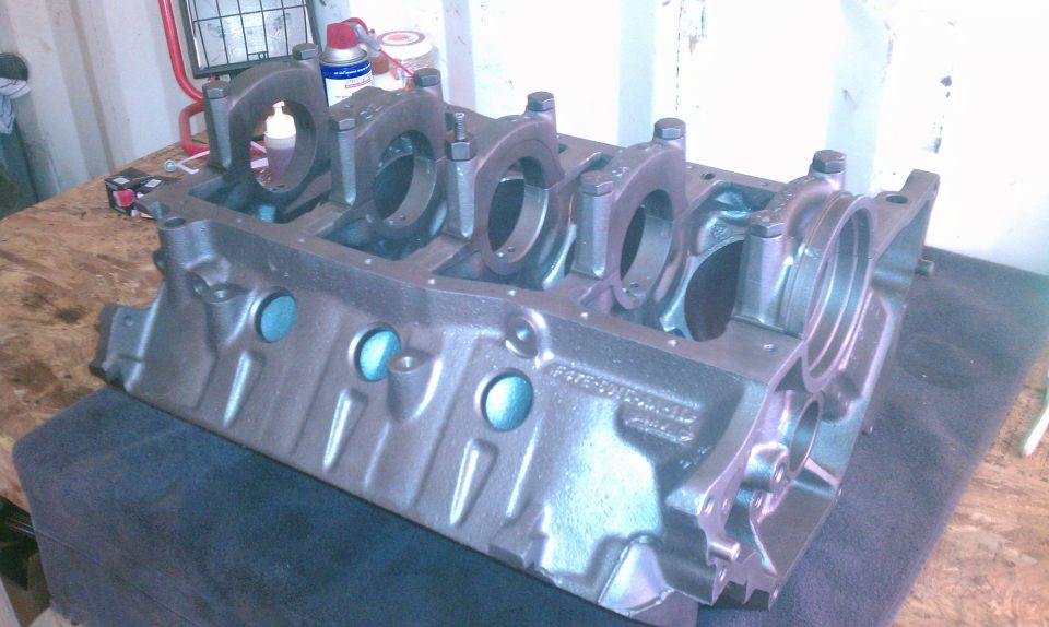 Engine block with main bearing caps installed. Text visible on the side