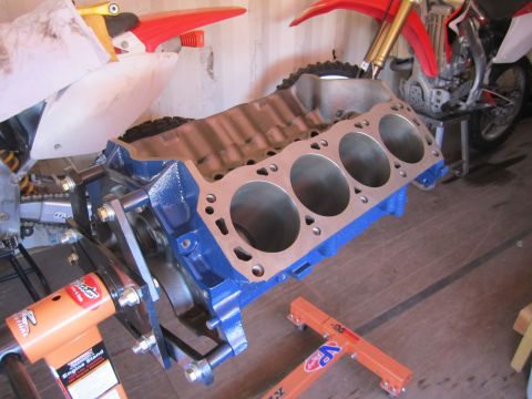 1996 Ford Bronco - A blue engine block is mounted on an engine stand, with motorcycles visible behind it.