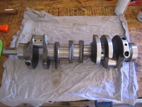 1996 Ford Bronco - A metal crankshaft rests on a grey cloth on a workbench.