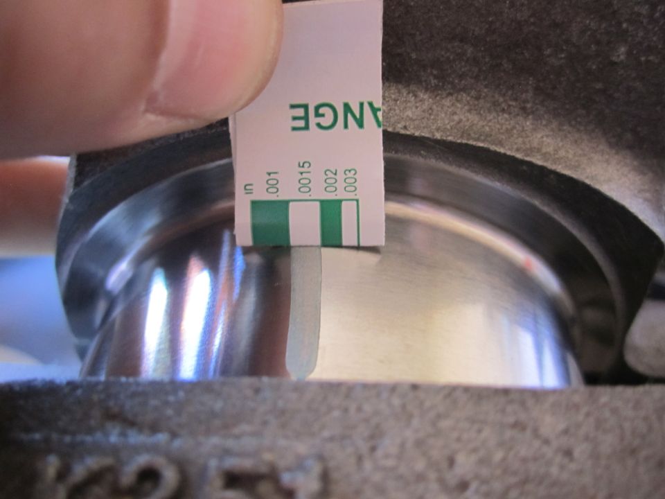 Feeler gauge measuring clearance on engine component. Text on gauge reads 'CHANGE' and measurements in inches