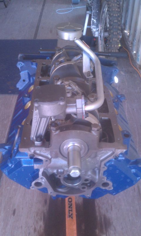 1996 Ford Bronco - Engine block assembly with oil pan and pickup tube visible, set against a workshop background.