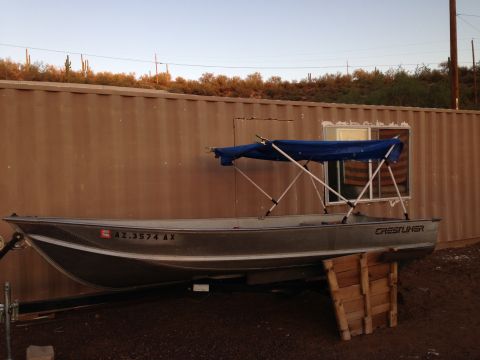 1996 Ford Bronco - Aluminum boat with blue canopy and registration AZ.3574 AX is parked next to a corrugated metal wall.
