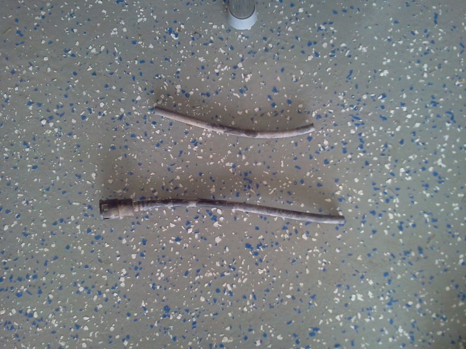 Two old dirty hose sections, one with a quick-connect fitting, on a speckled garage floor