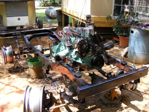 Vehicle frame and engine assembly on jack stands outdoors