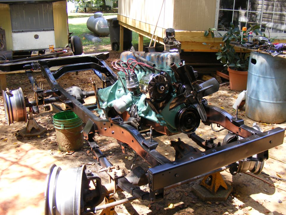 Vehicle frame and engine assembly on jack stands outdoors