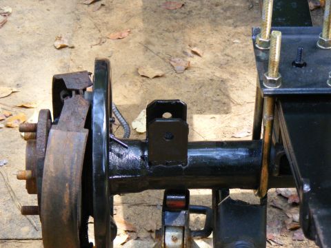 Rear axle assembly with brake drum and suspension bracket. Supermotors.net logo visible