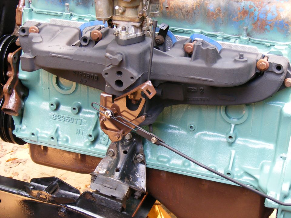Engine block with carburetor and intake manifold, teal paint, close-up view