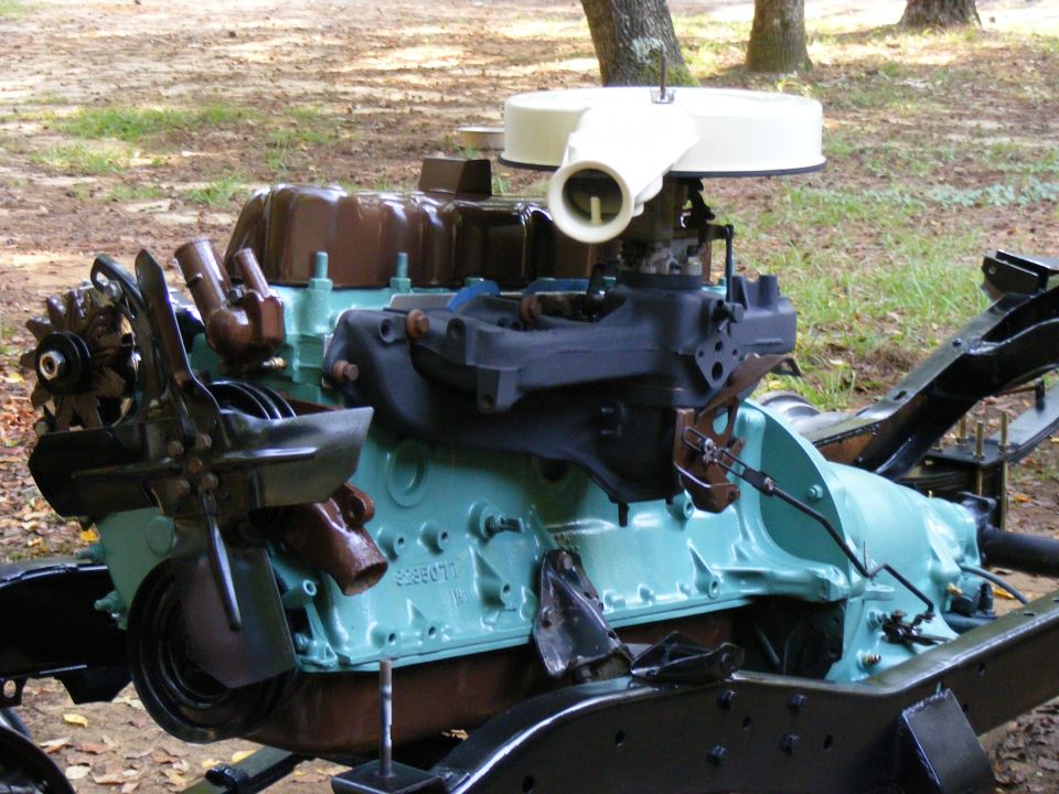 Engine assembly with turquoise block, brown valve covers, and air cleaner. Mounted on black frame pieces