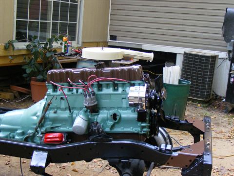 Engine assembly on a black frame, painted teal and brown, with red spark plug wires