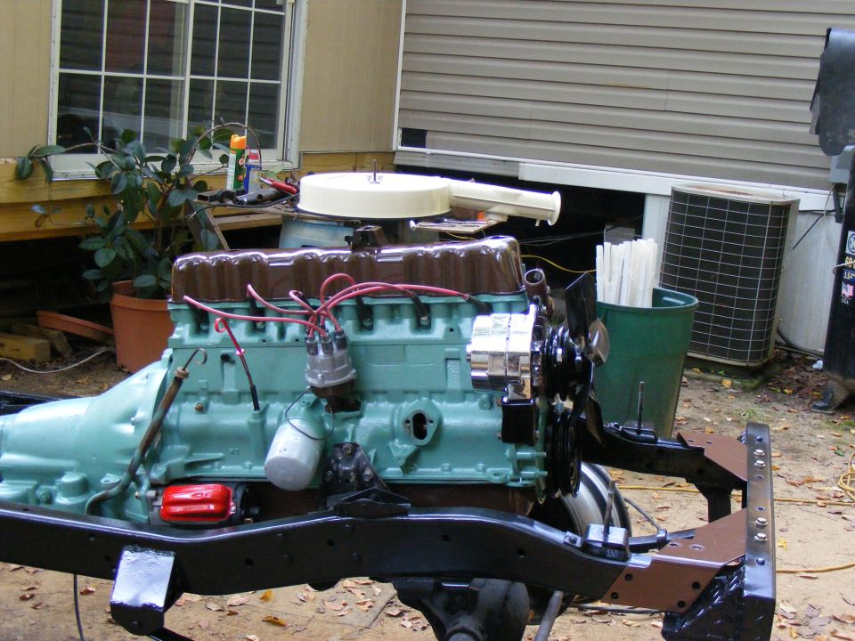 Engine assembly on a black frame, painted teal and brown, with red spark plug wires