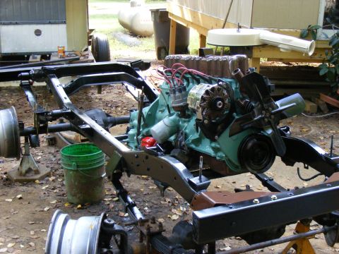 Vehicle frame and engine assembly on jack stands outdoors