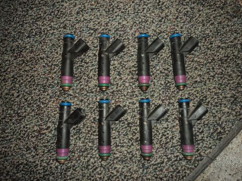 2004 Mercury Grand Marquis - Eight fuel injectors are laid out on a carpeted surface, with a SuperMotors.net watermark in the lower right corner.