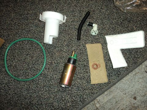 2004 Mercury Grand Marquis - A collection of fuel system components, including a fuel pump, filter, O-ring, and adapter, are laid out on a carpeted surface.