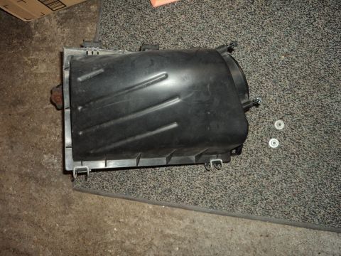2004 Mercury Grand Marquis - A black plastic air intake box is shown, with two washers nearby on a carpeted floor.